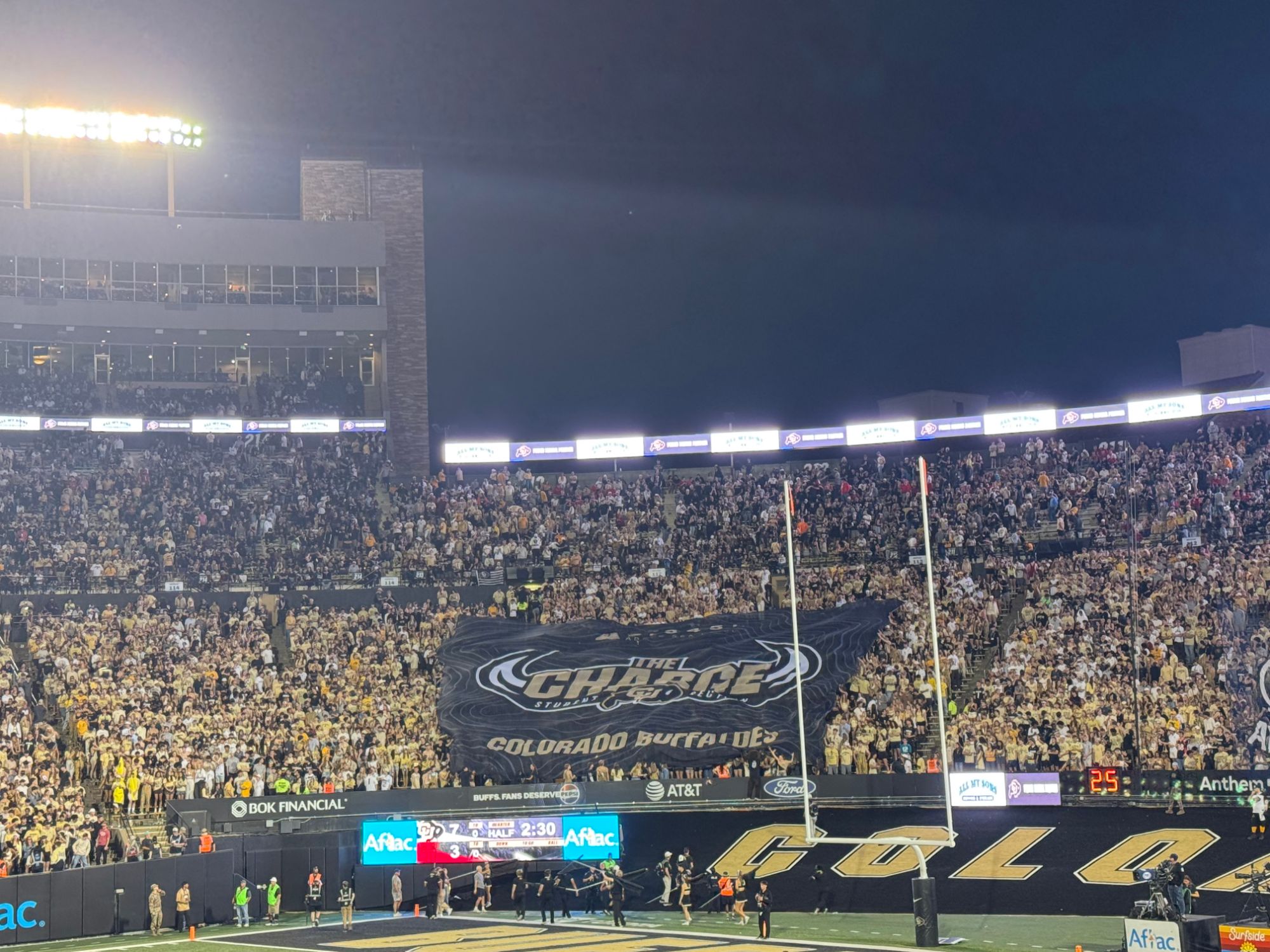 Folsom Field at night during Colorado's game against Texas Tech, with the student section banner out and the scoreboard showing Colorado 7, Texas Tech 3 late in the first half.